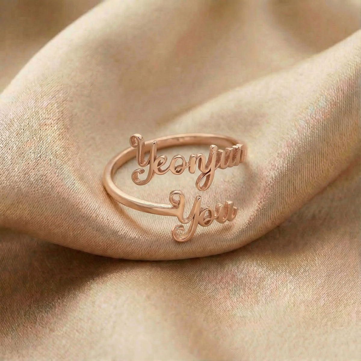 Personalized name ring, one-size in rose gold finish on beige silk fabric