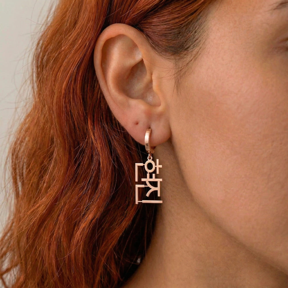 Personalized name drop earrings in Korean in rose gold finish worn on ear, side profile view