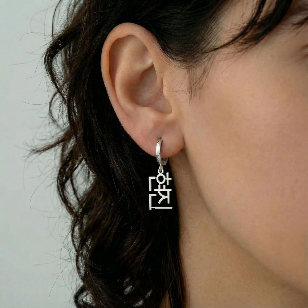 Personalized name drop earrings in Korean in silver finish worn on ear, side profile view