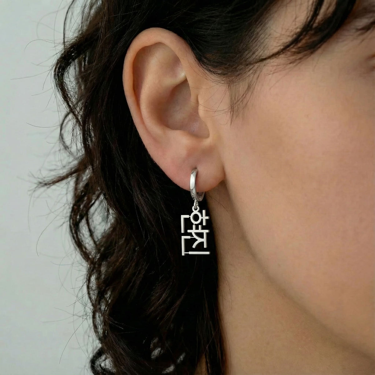 Personalized name drop earrings in Korean in silver finish worn on ear, side profile view