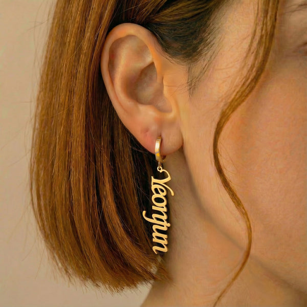Personalized name drop earrings in gold finish worn on ear, side profile view