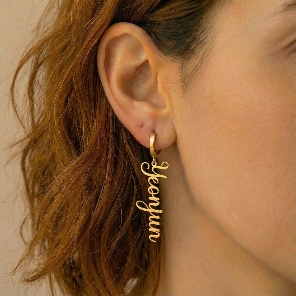 Personalized name drop earrings in gold finish worn on ear, side profile view