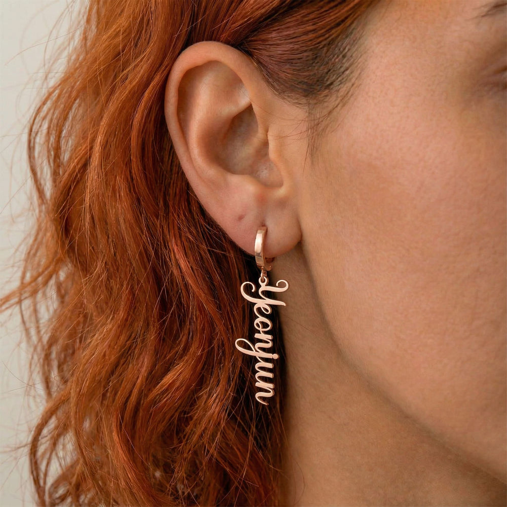 Personalized name drop earrings in rose gold finish worn on ear, side profile view