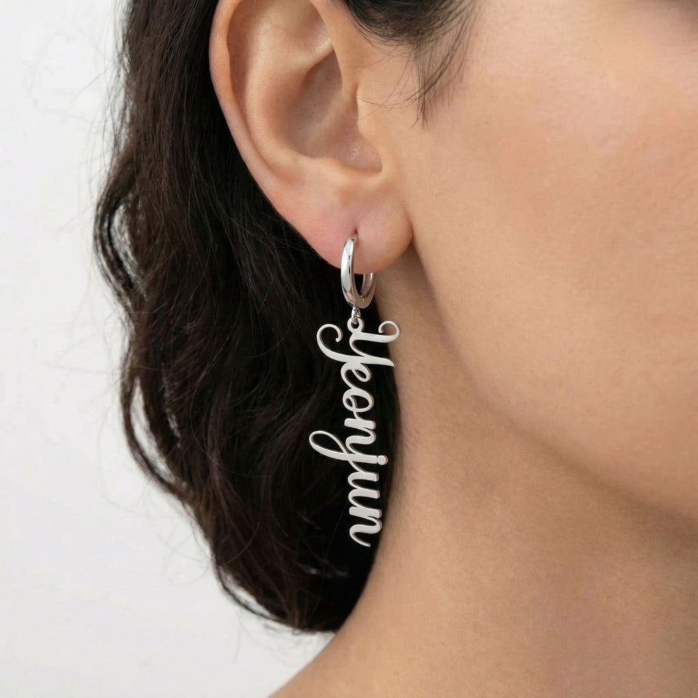 Personalized name drop earrings in silver finish worn on ear, side profile view