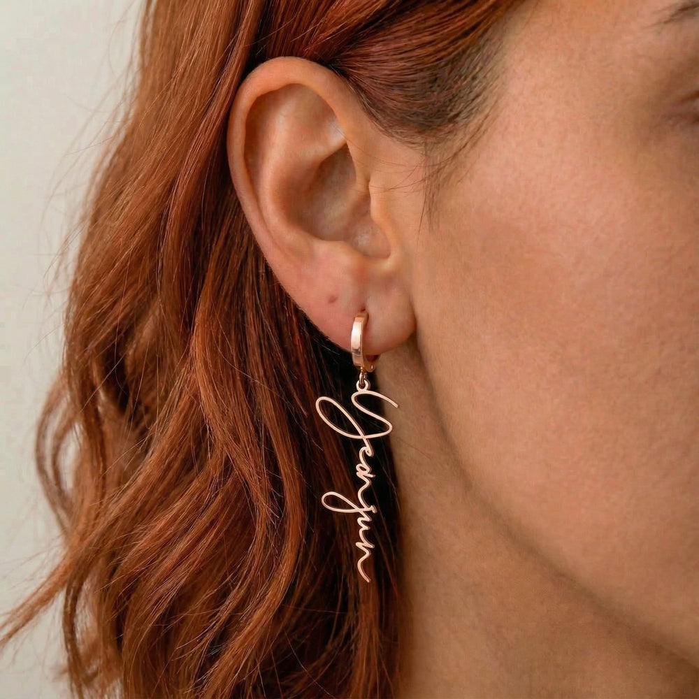 Personalized name drop earrings in rose gold finish worn on ear, side profile view