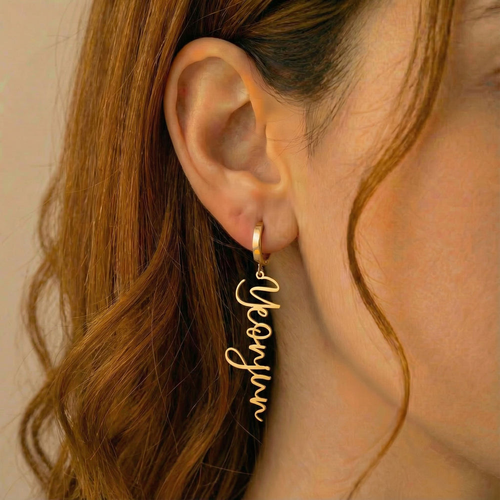 Personalized name drop earrings in gold finish worn on ear, side profile view