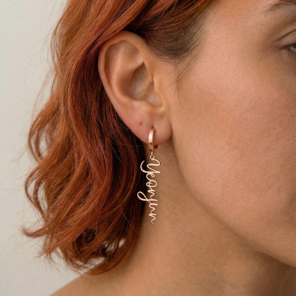 Personalized name drop earrings in rose gold finish worn on ear, side profile view