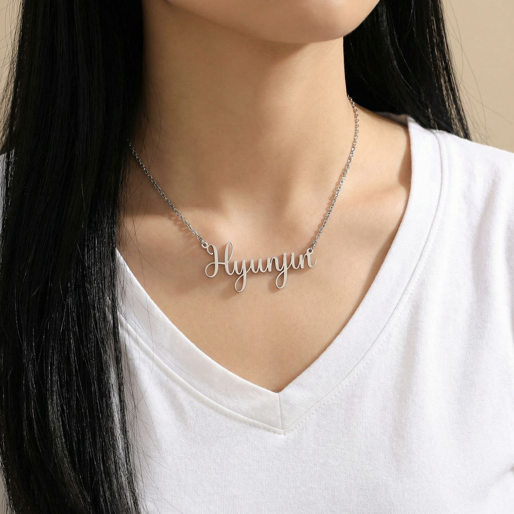 Silver Latin script K-pop idol name necklace reading Hyunjin worn on woman’s neck