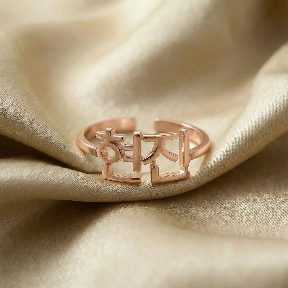 Personalized name ring in Korean, one-size in rose gold finish on beige silk fabric