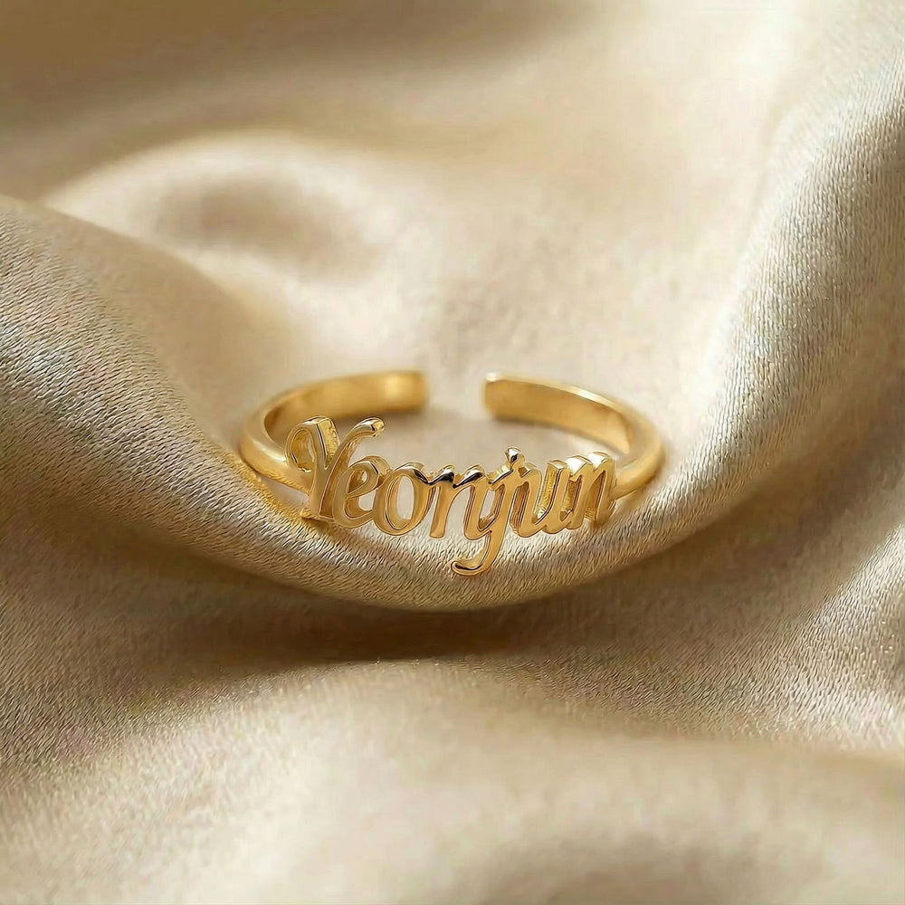Personalized name ring, one-size in gold finish on beige silk fabric