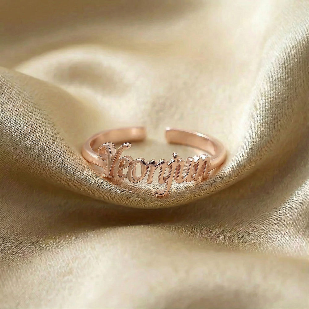 Personalized name ring, one-size in rose gold finish on beige silk fabric