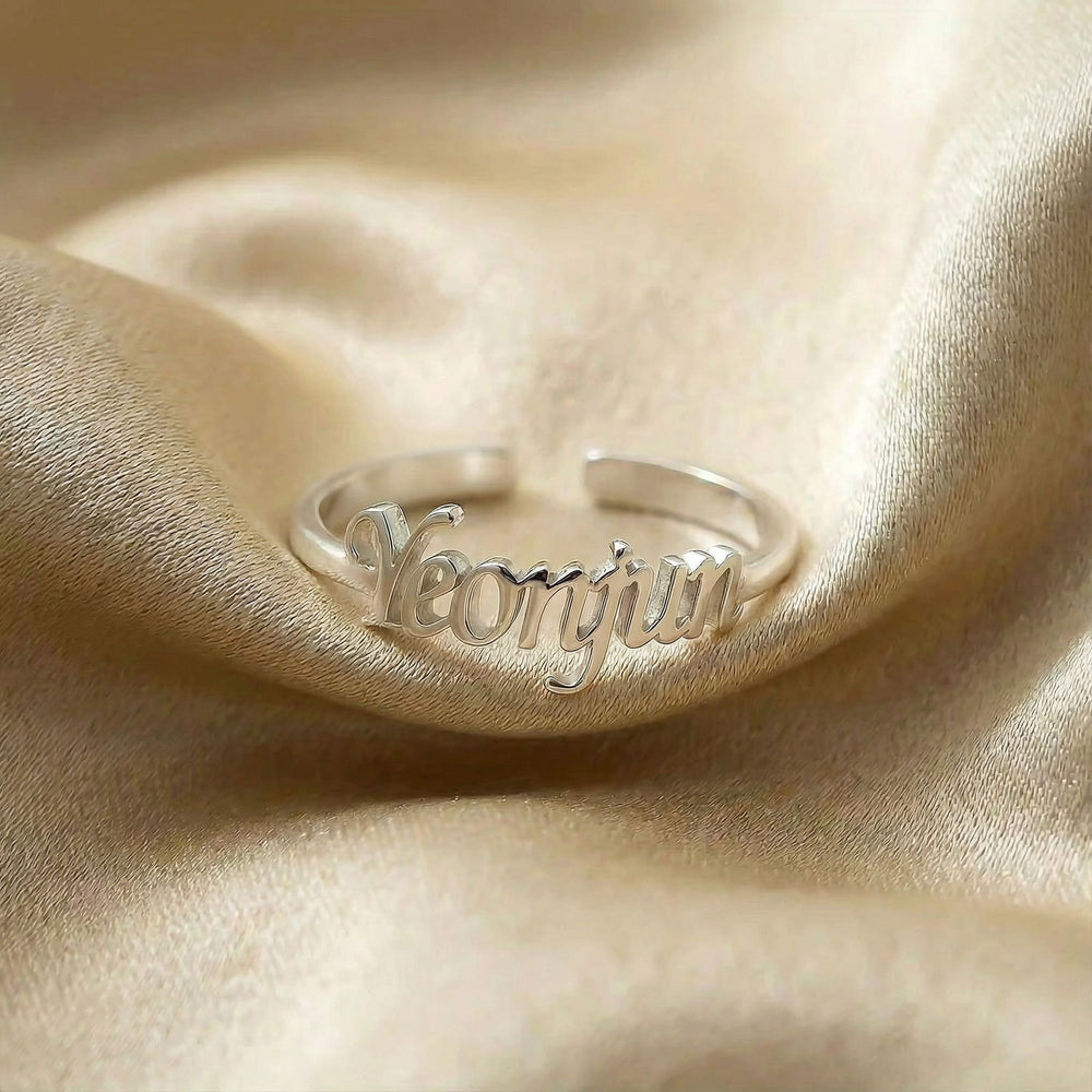 Personalized name ring, one-size in silver finish on beige silk fabric
