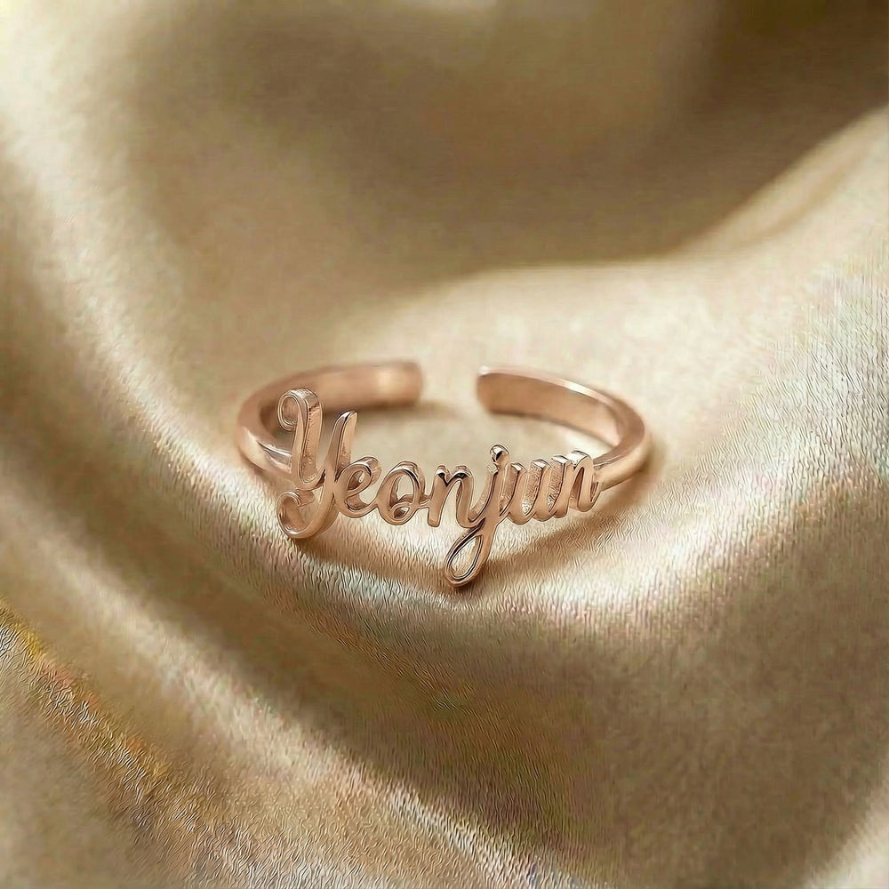 Personalized name ring, one-size in rose gold finish on beige silk fabric