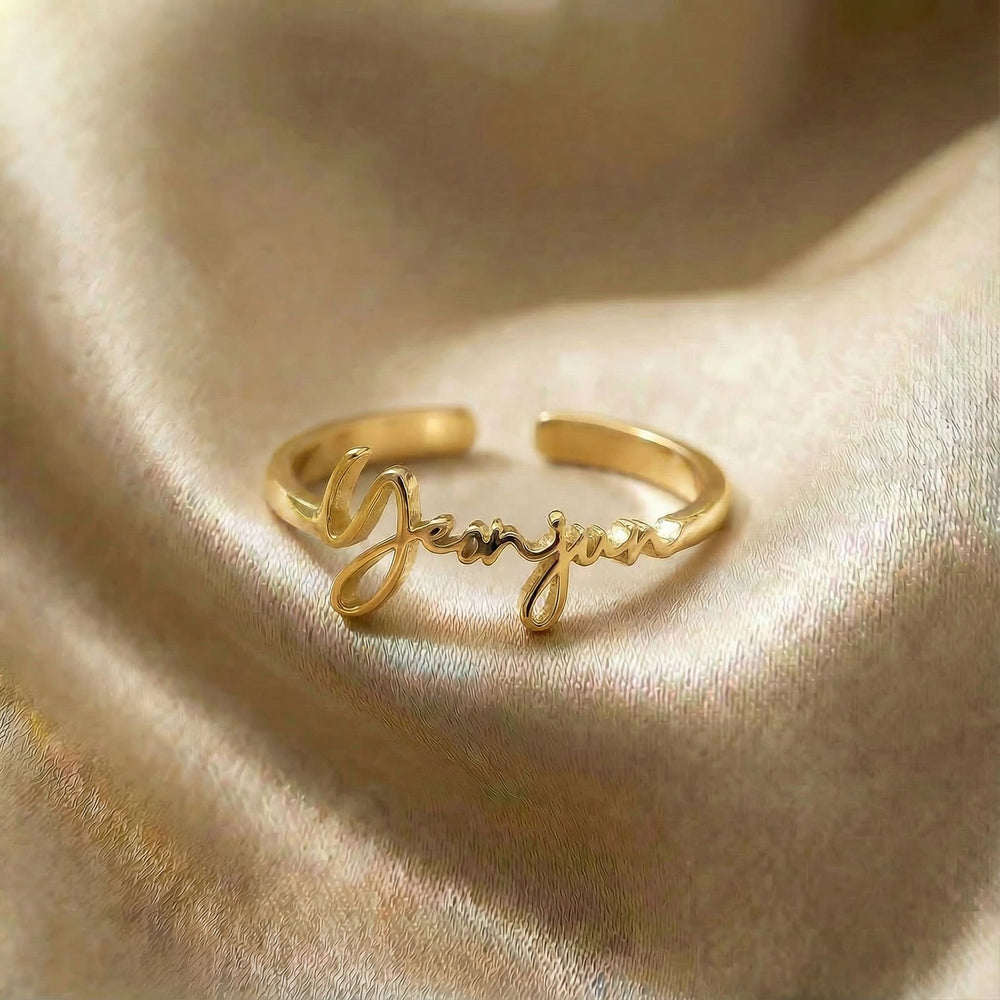 Personalized name ring, one-size in gold finish on beige silk fabric