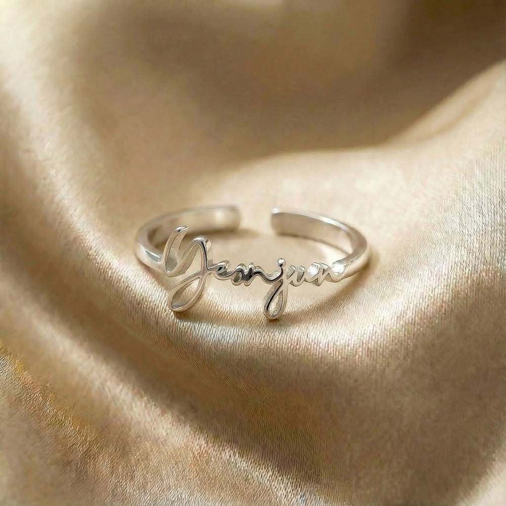 Personalized name ring, one-size in silver finish on beige silk fabric