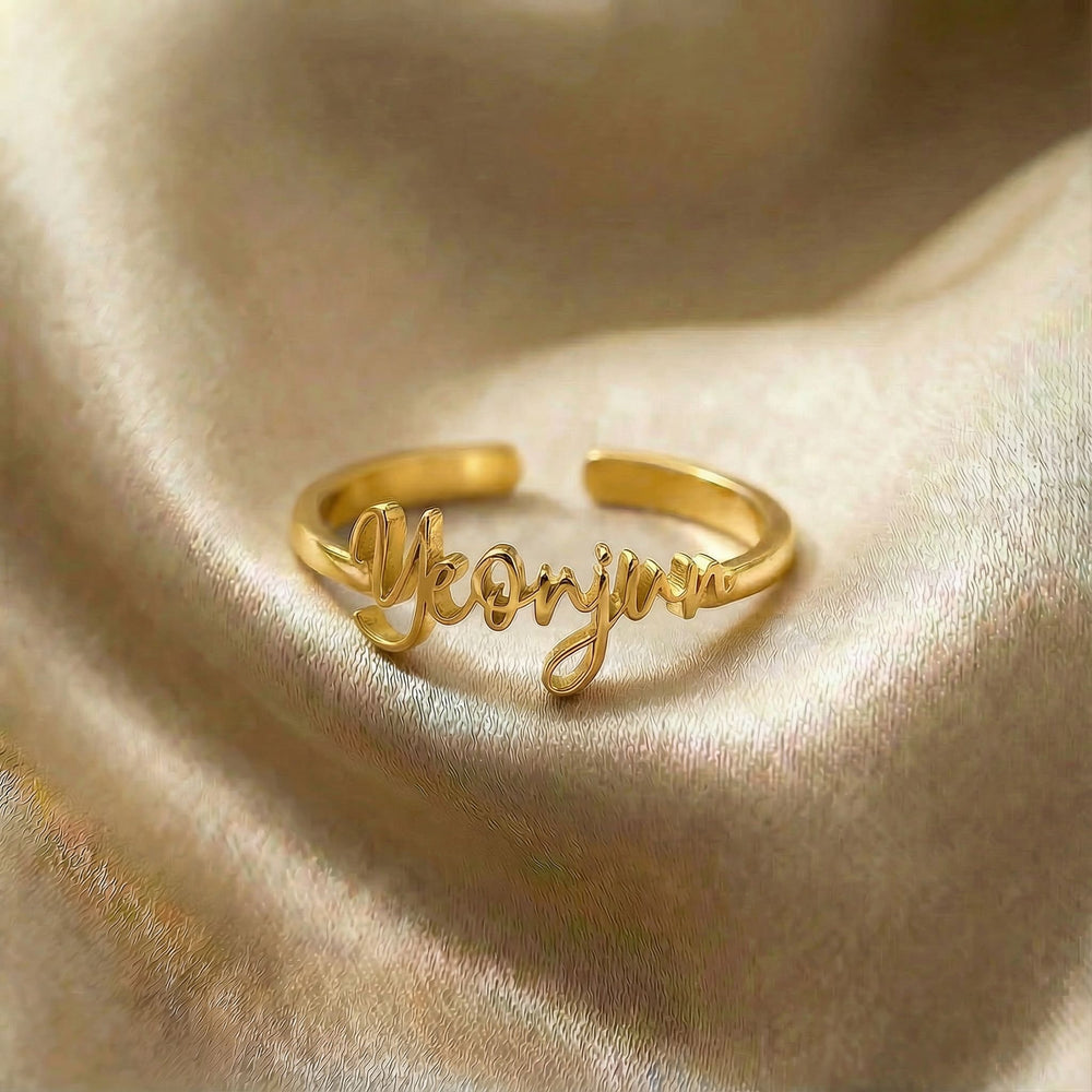Personalized name ring, one-size in gold finish on beige silk fabric