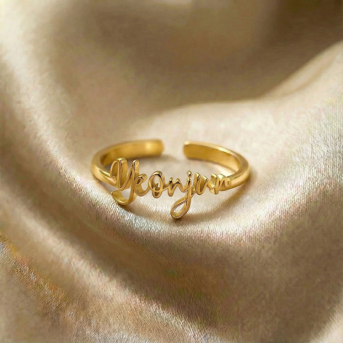 Personalized name ring, one-size in gold finish on beige silk fabric