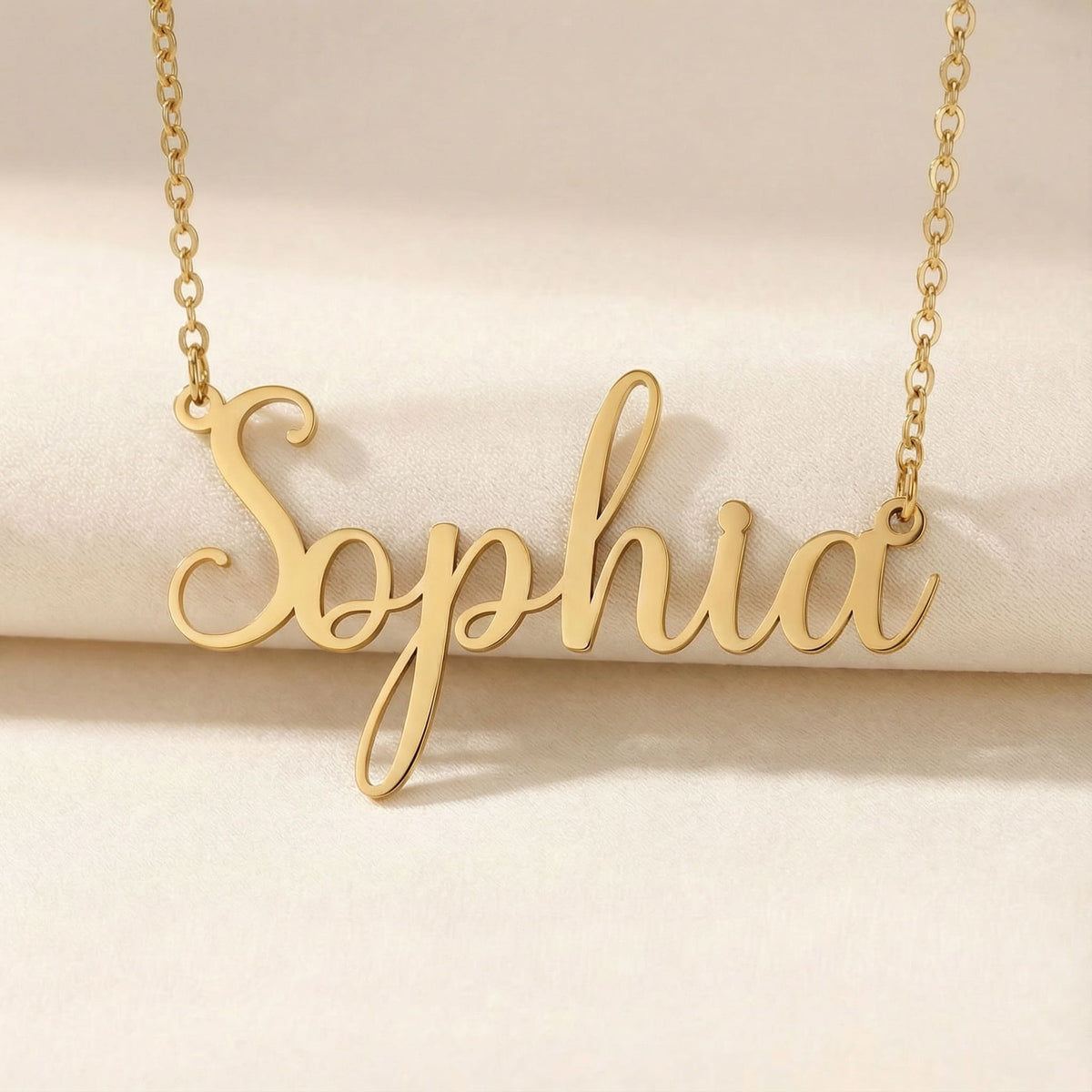 Personalized name necklace in gold finish on beige silk fabric