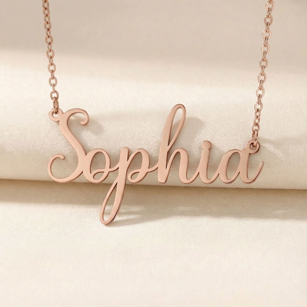 Personalized name necklace in rose gold finish on beige silk fabric