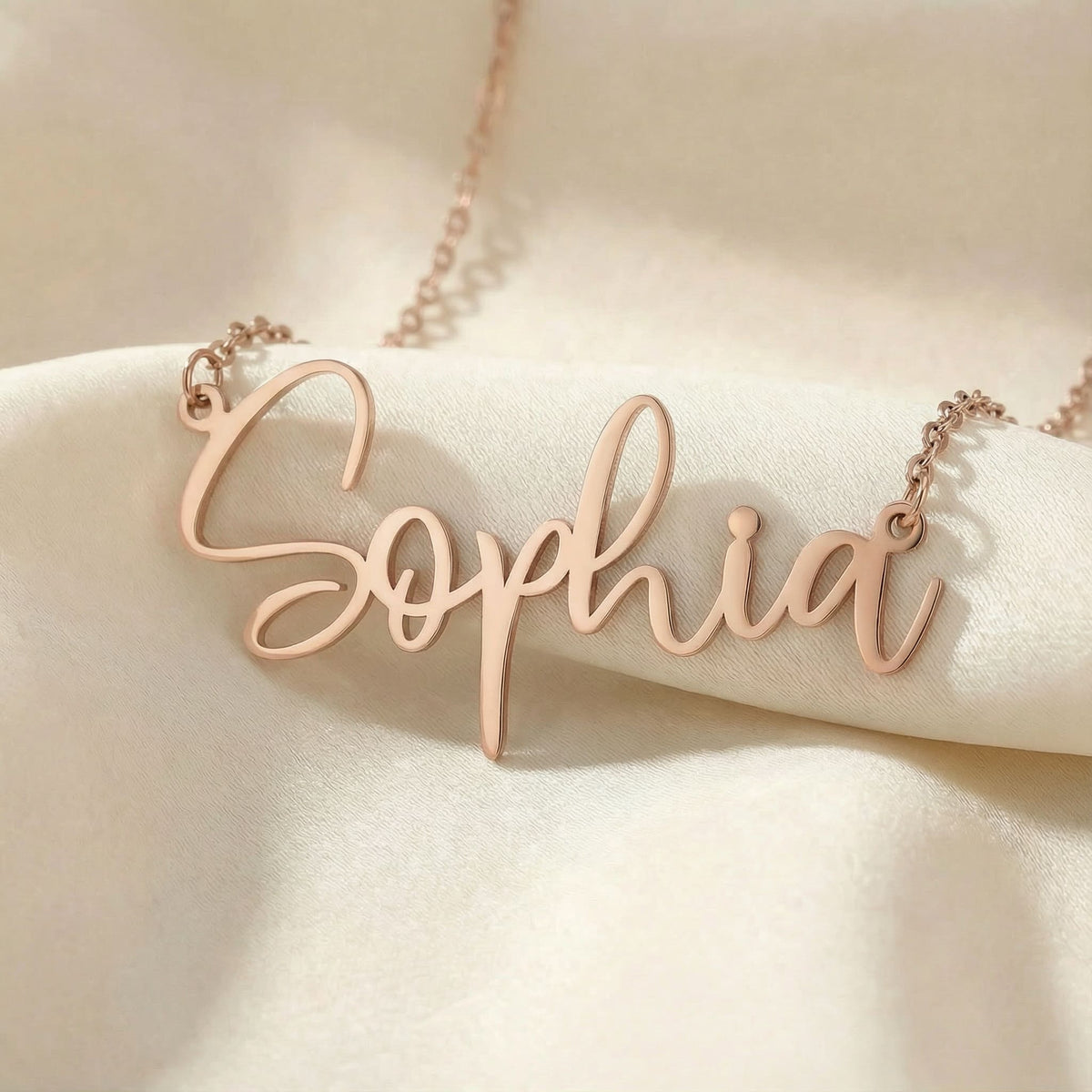 Personalized name necklace in rose gold finish on beige silk fabric