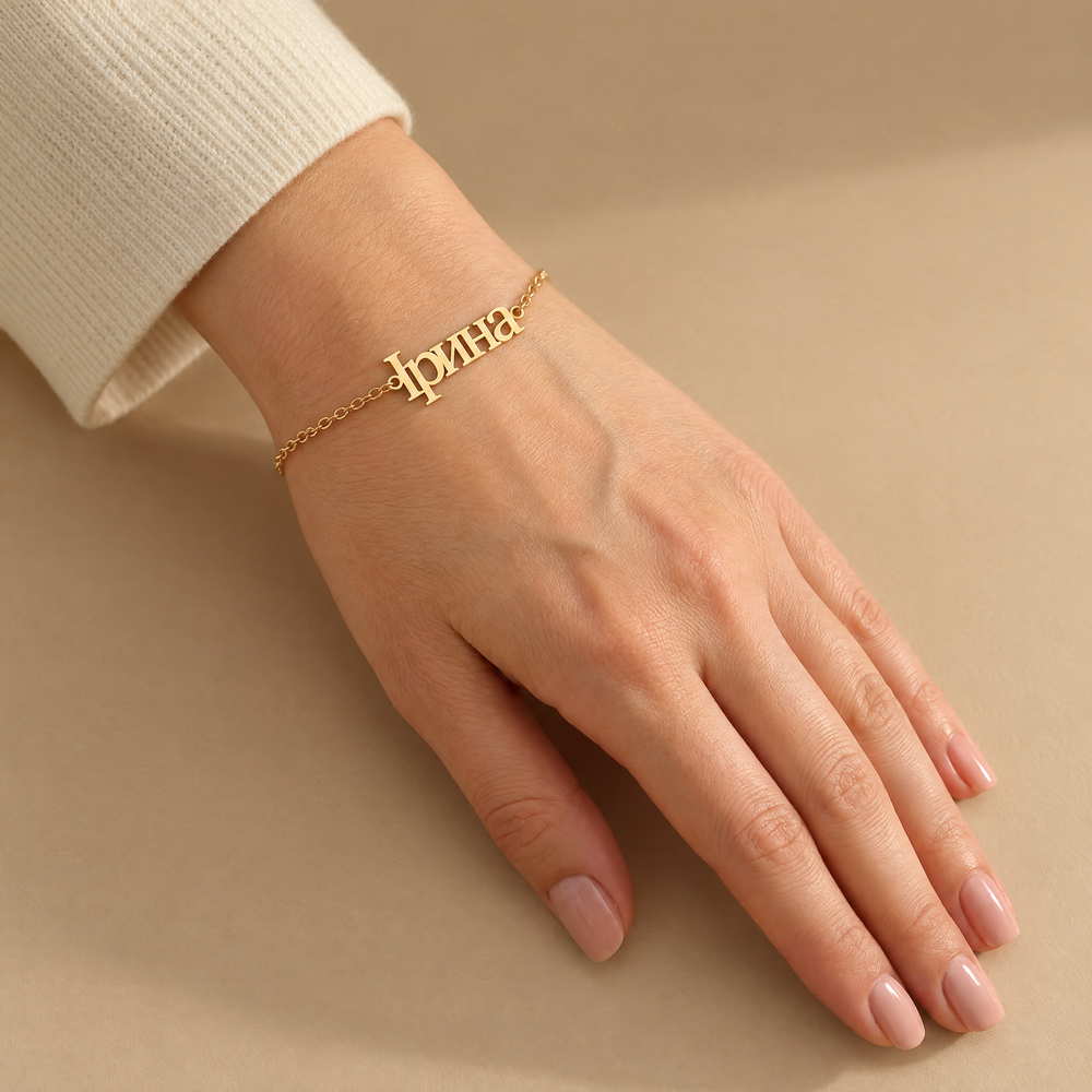Woman's wrist wearing a personalized Ukrainian name bracelet reading Ірина in 18K gold plating