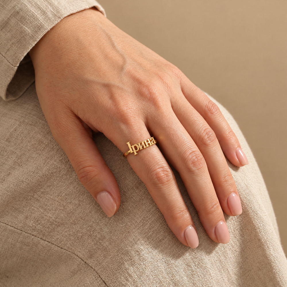 Woman's hand wearing a personalized Ukrainian name ring reading Ірина in 18K gold plating