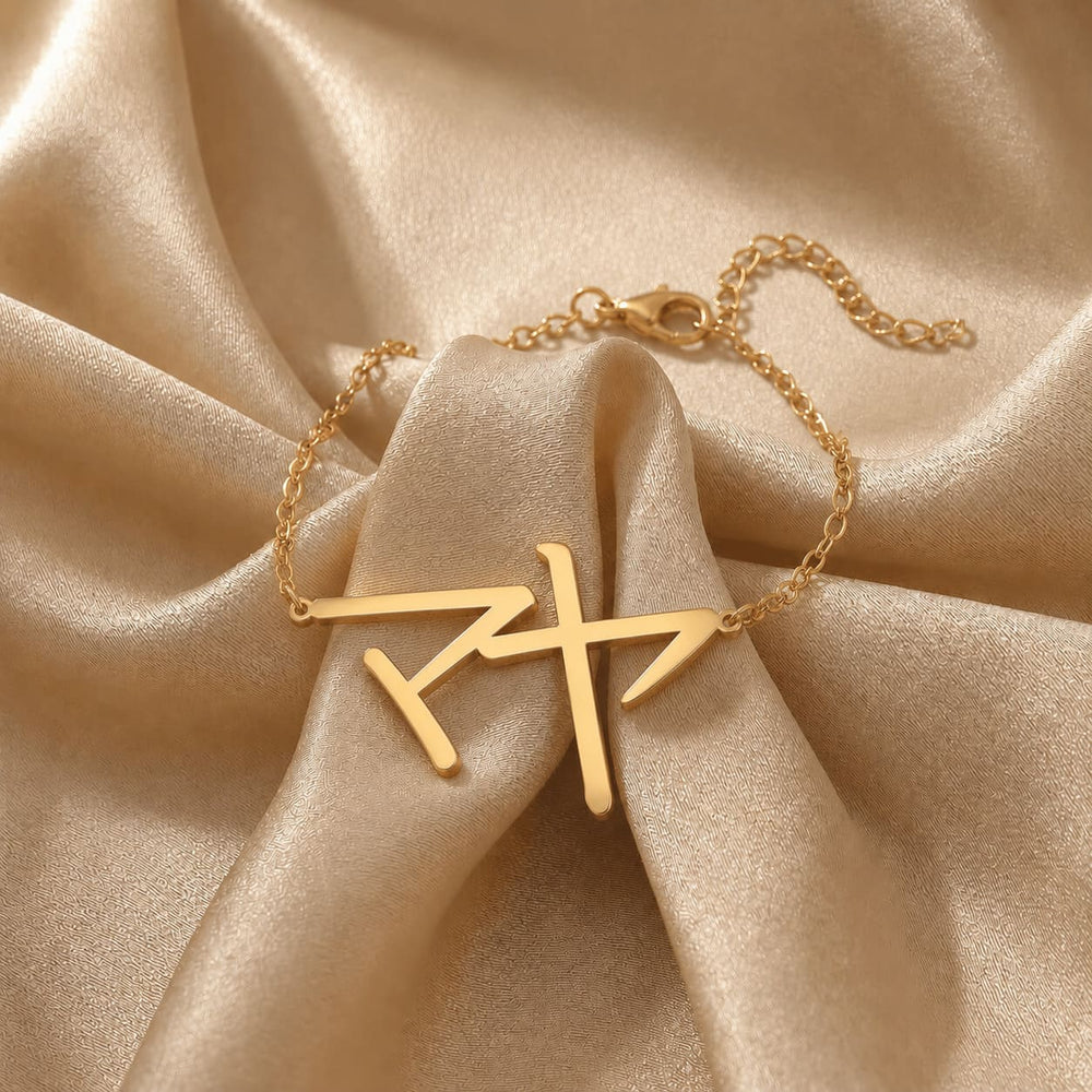 Gold bracelet with a Japanese Katakana pendant meaning "Maya" on beige fabric
