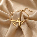 Gold bracelet with a Japanese Katakana pendant meaning "Maya" on beige fabric