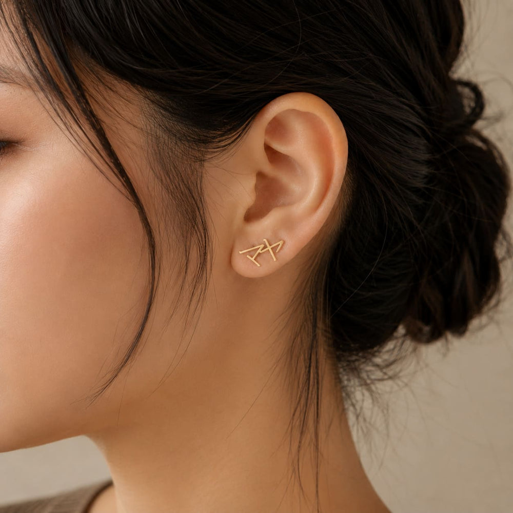 Close-up of gold Japanese Katakana ear climber earrings meaning "Maya"