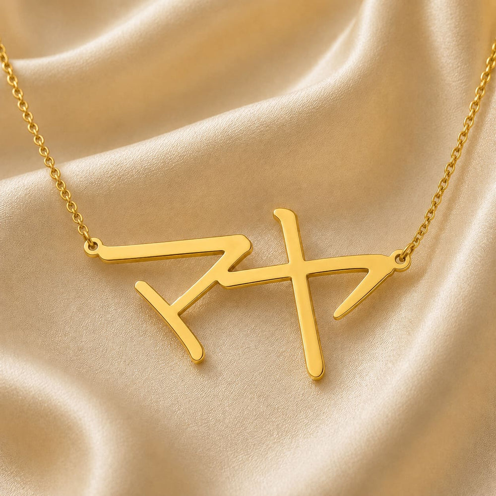Gold necklace with a Japanese Katakana pendant meaning "Maya" on a beige fabric background