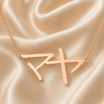 Rose gold necklace with a Japanese Katakana pendant meaning "Maya" on a beige satin background